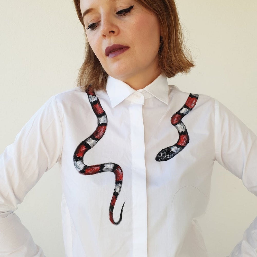 A crisp white button-down shirt from Daria Creative adorned with a hand-painted snake