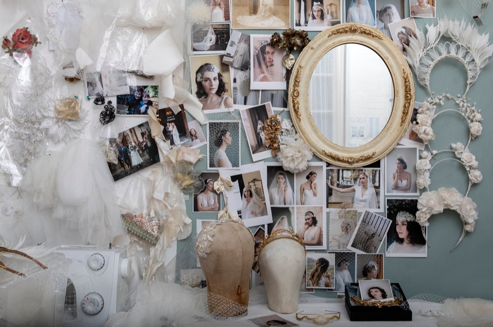 Rae's small London studio space, featuring a desk covered in tulle and tiaras and a wall pinned with model shots and fabric scraps.