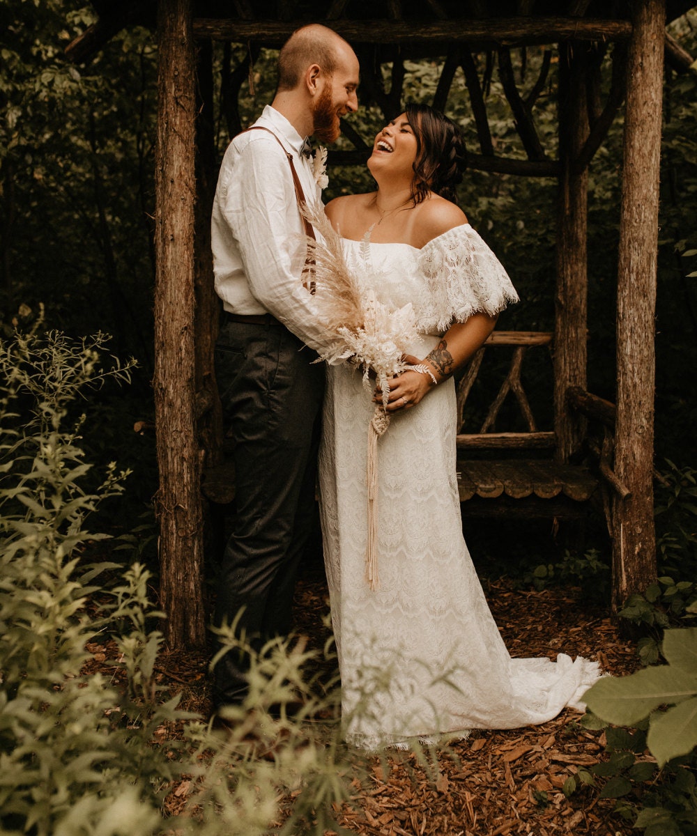 A portrait of Sarah and Chris Schalago in front of a rustic gazebo on their wedding day.