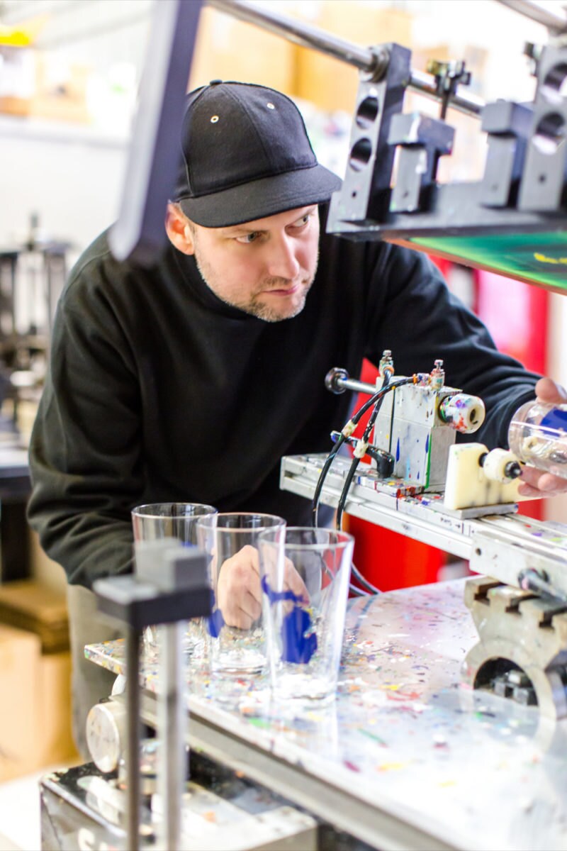 Brett works on printing states onto pint glasses using a glass press.