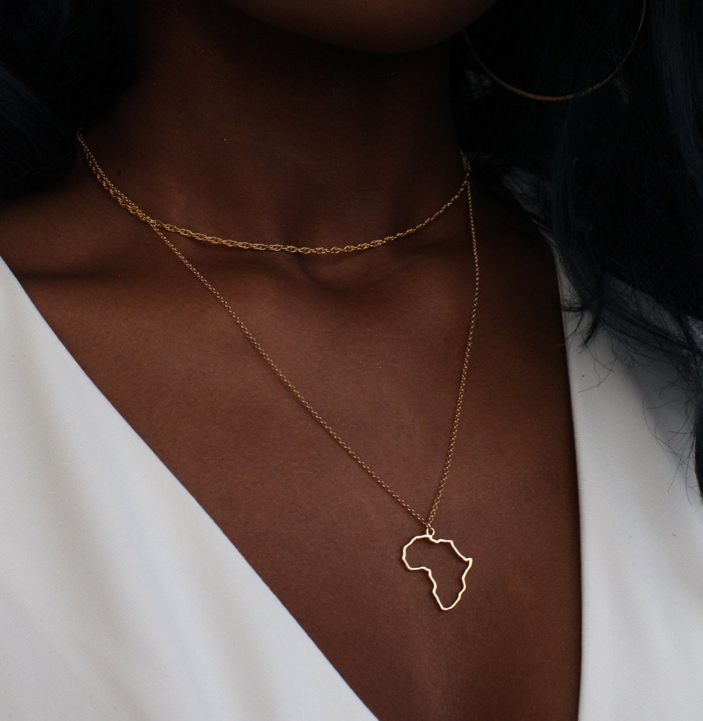 A woman models an Africa outline necklace from Omi Woods