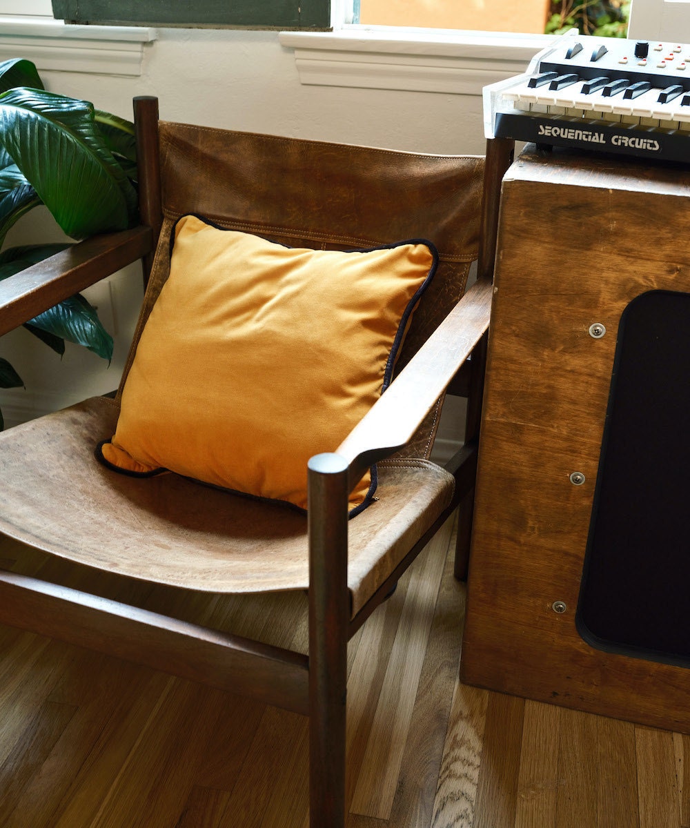 A vintage leather slingback chair styled with a mustard-colored velvet throw pillow from Soft Home Textile on Etsy.