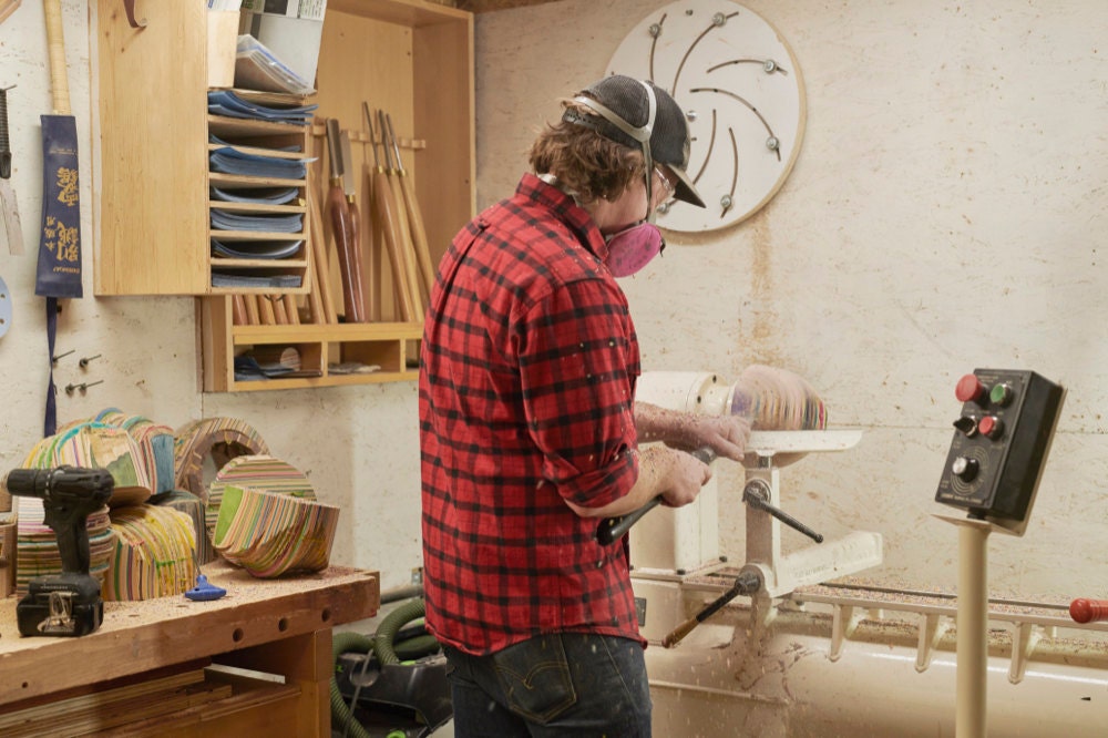 Martinus turns a piece of WIP wood on a lathe.