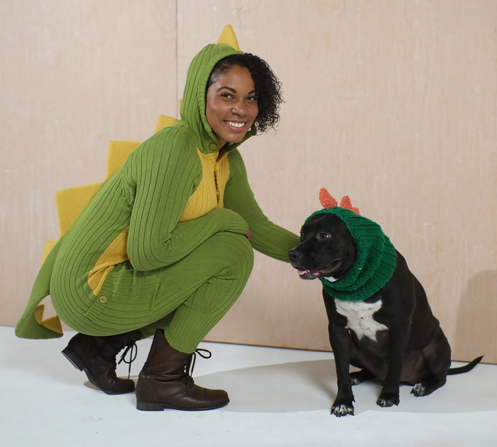 A woman and her dog, both dressed up as dinosaurs.