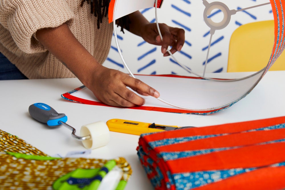 Natalie affixes colorful fabric to a drum-shaped lampshade frame