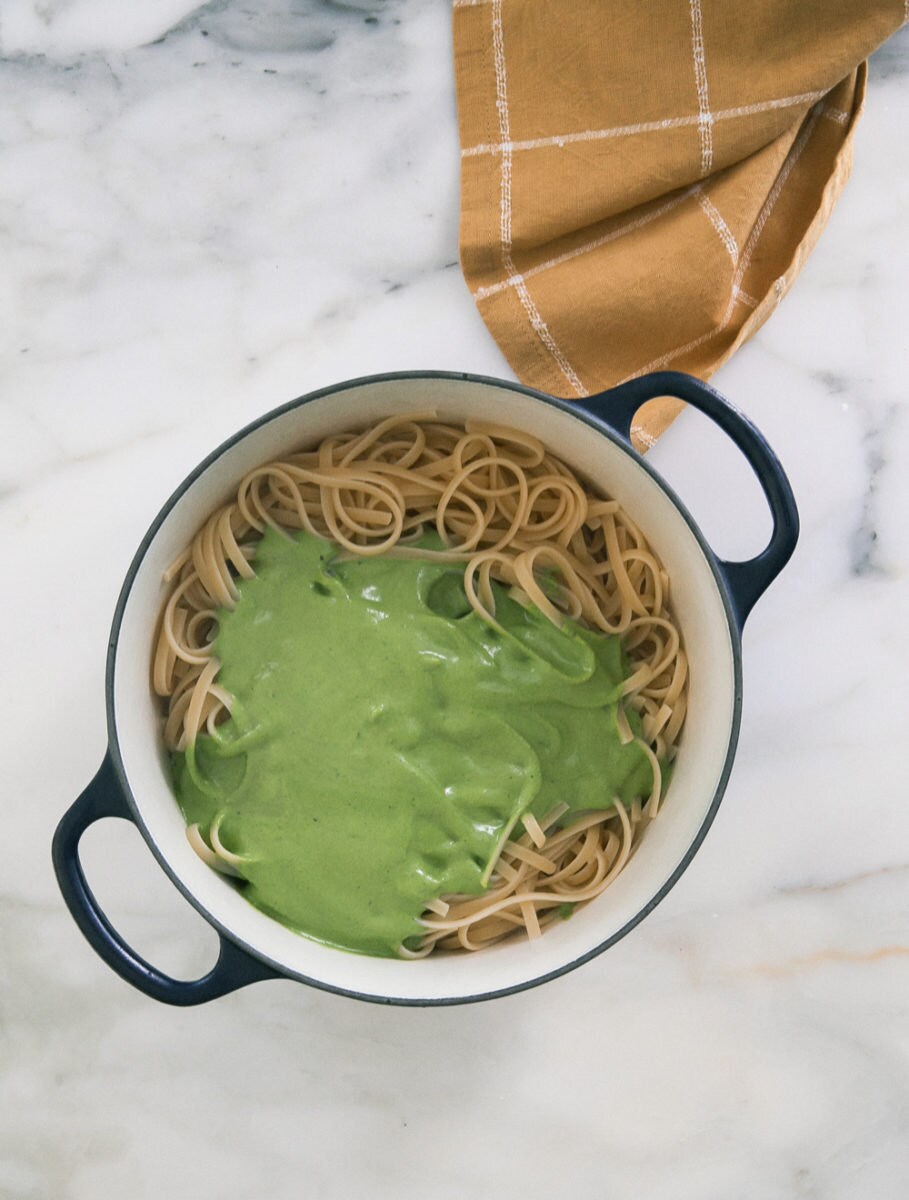 Green sauce poured generously over a pot of pasta