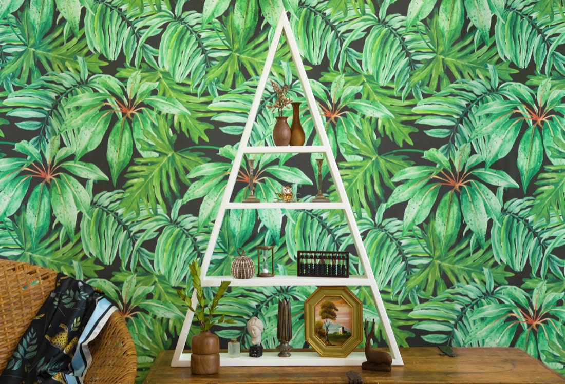 A shelf styled with earthy, natural accents and displayed in front of lush, green, jungle-themed wallpaper.