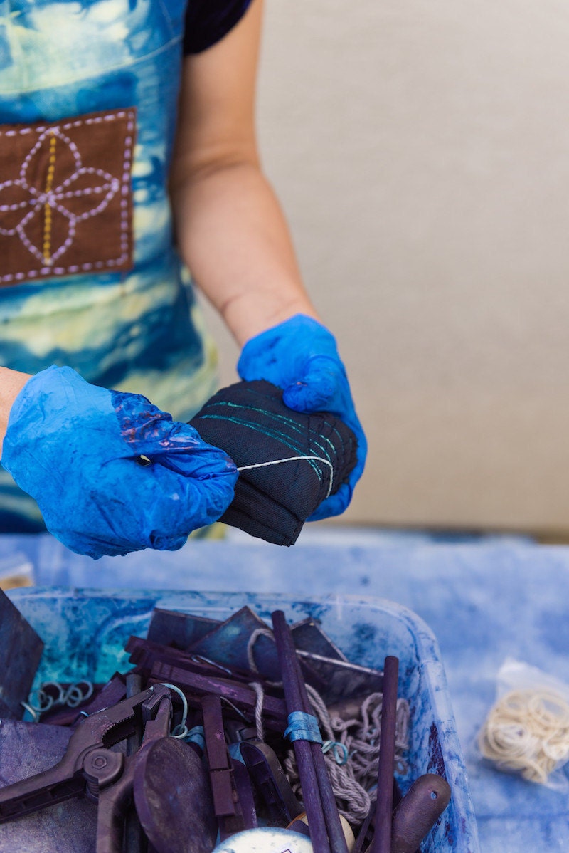 Rajni removes rubber bands from a freshly dyed piece of fabric