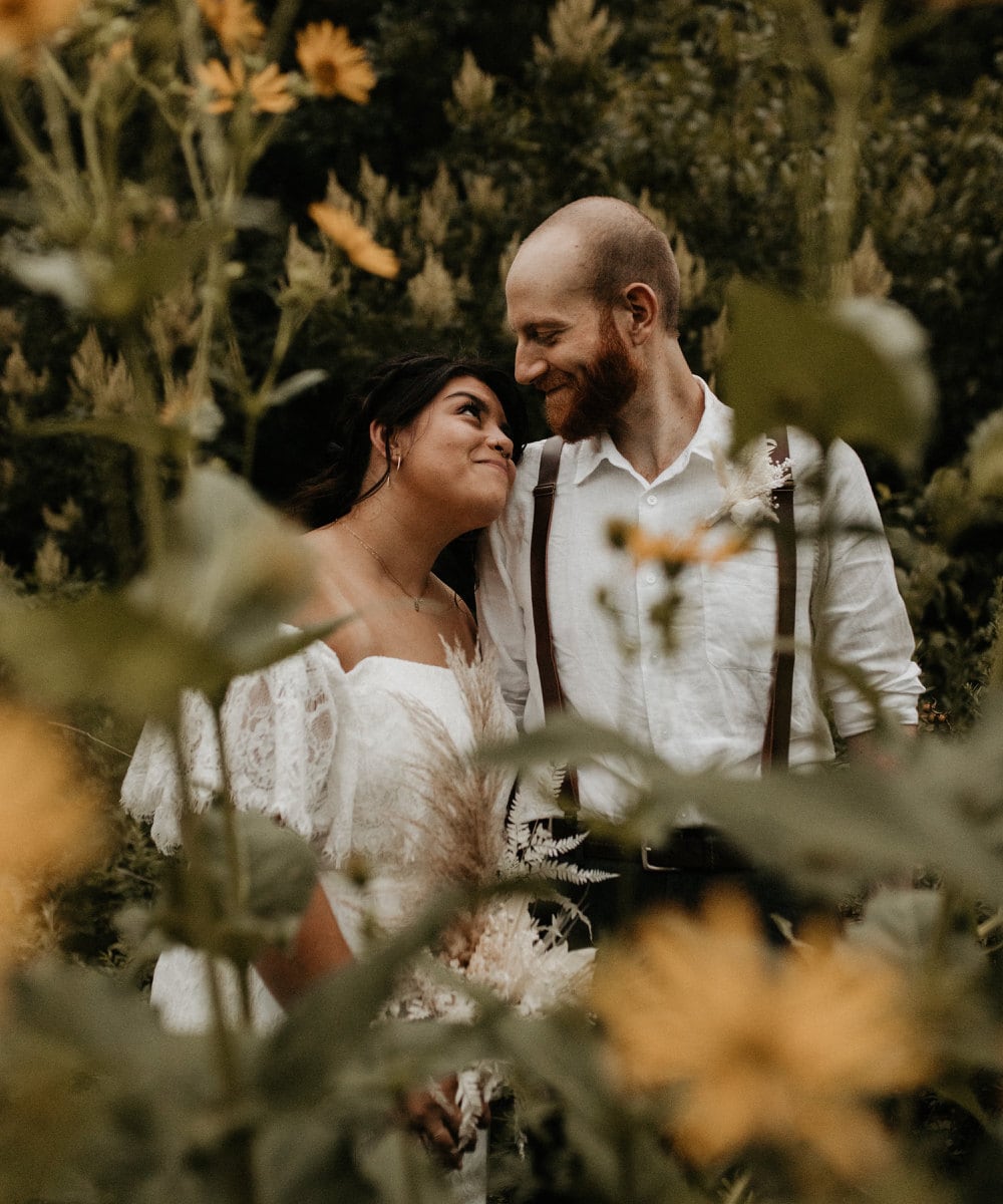 A portrait of Sarah and Chris Schalago standing in a meadow on their wedding day.