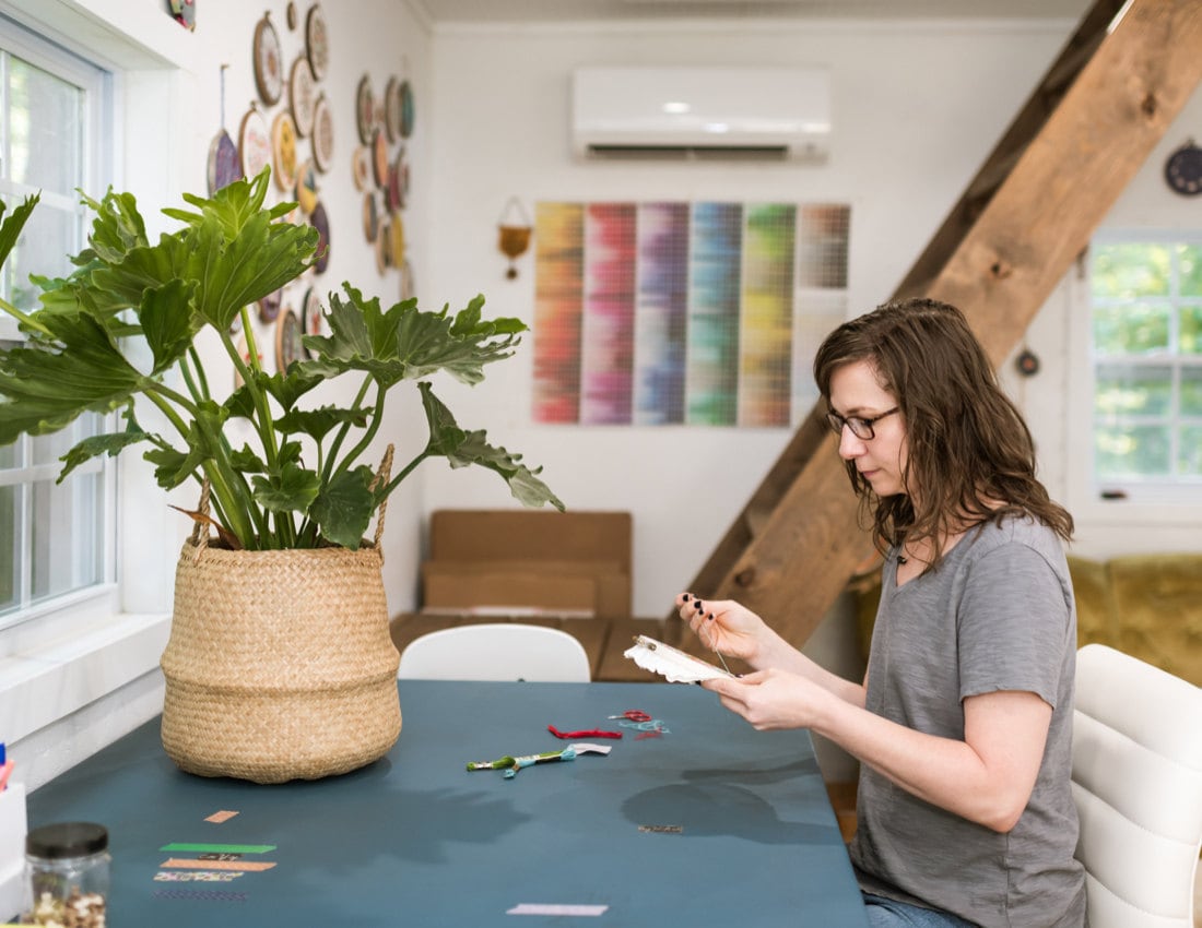 Liz at her desk, working on an embroidery hoop