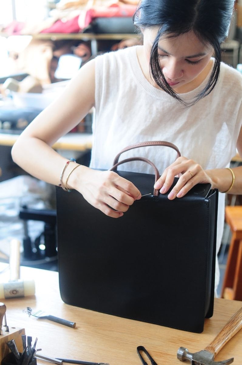 Joe sewing the handle on a leather bag