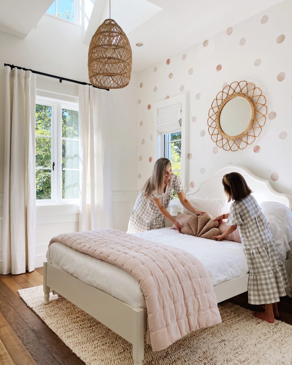 Kristine and her daughter make the bed, adding a shell throw pillow to the top.