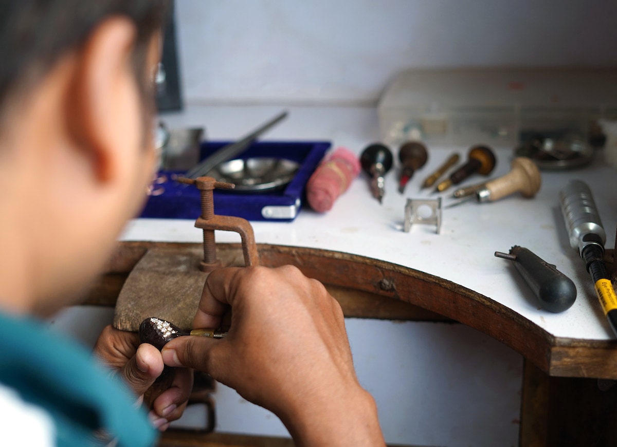 A member of the Abhika Jewels team sets a diamond ring at his workbench