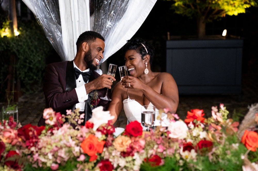 A portrait of Addy and Joel toasting at their sweetheart table on their wedding night.