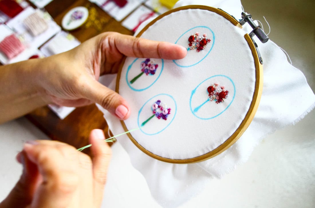 Ruby embroiders four separate jewelry designs on the same piece of fabric stretched over a larger hoop