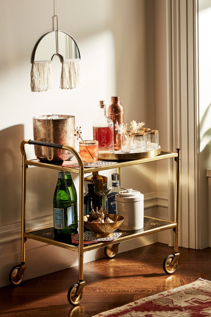 A vintage '60s bar cart featuring a custom spirit decanter, vintage highball glasses, and other cocktail-crafting essentials