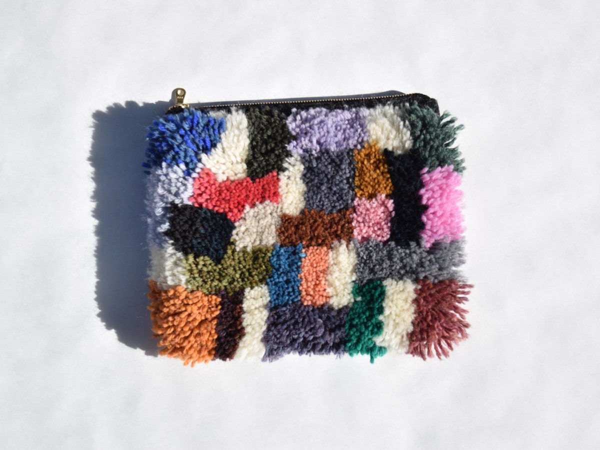 A colorful furry clutch made of yarn against a white background.