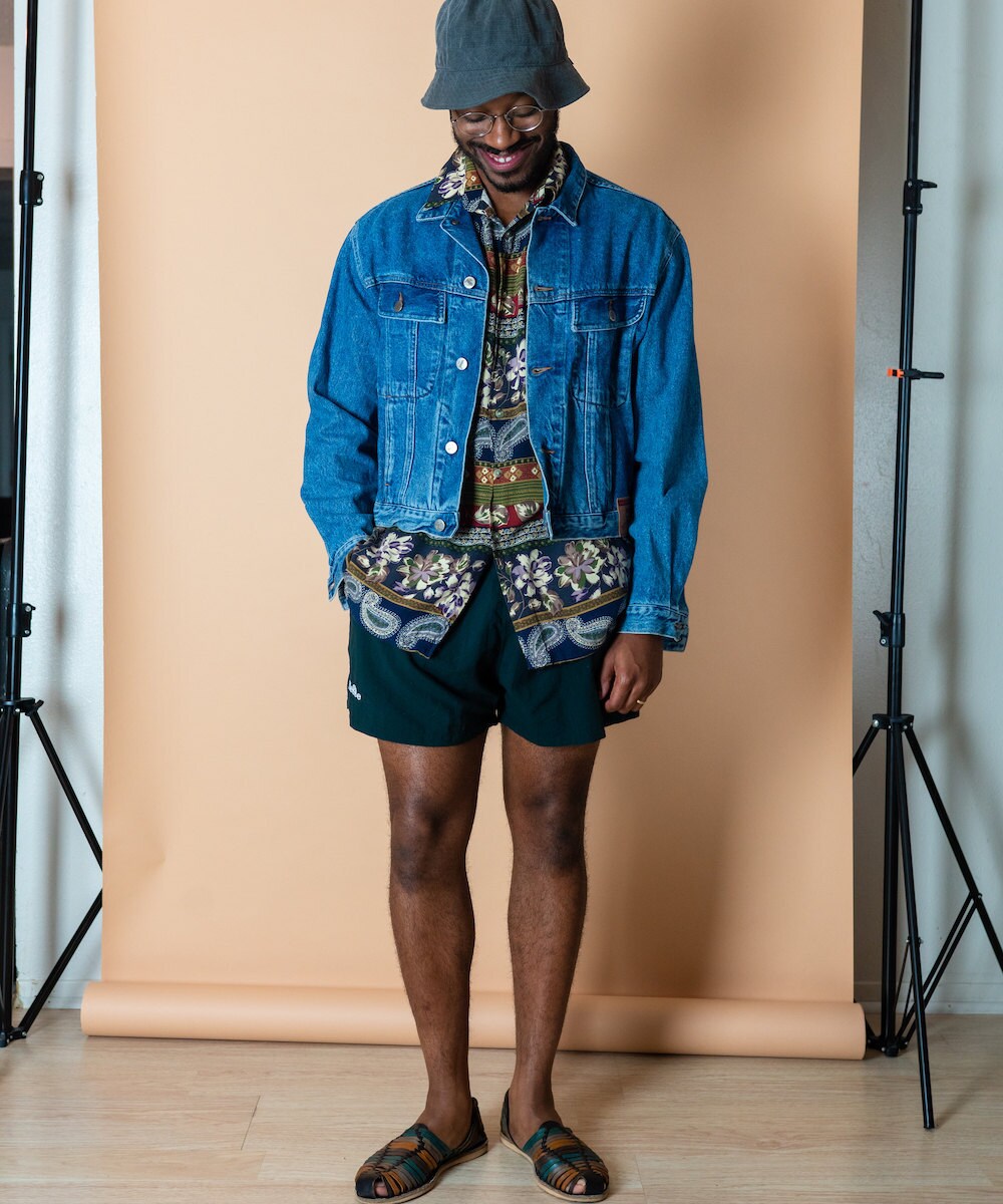 Norman models a paisley shirt, denim jacket, and shorts from MAW SUPPLY.