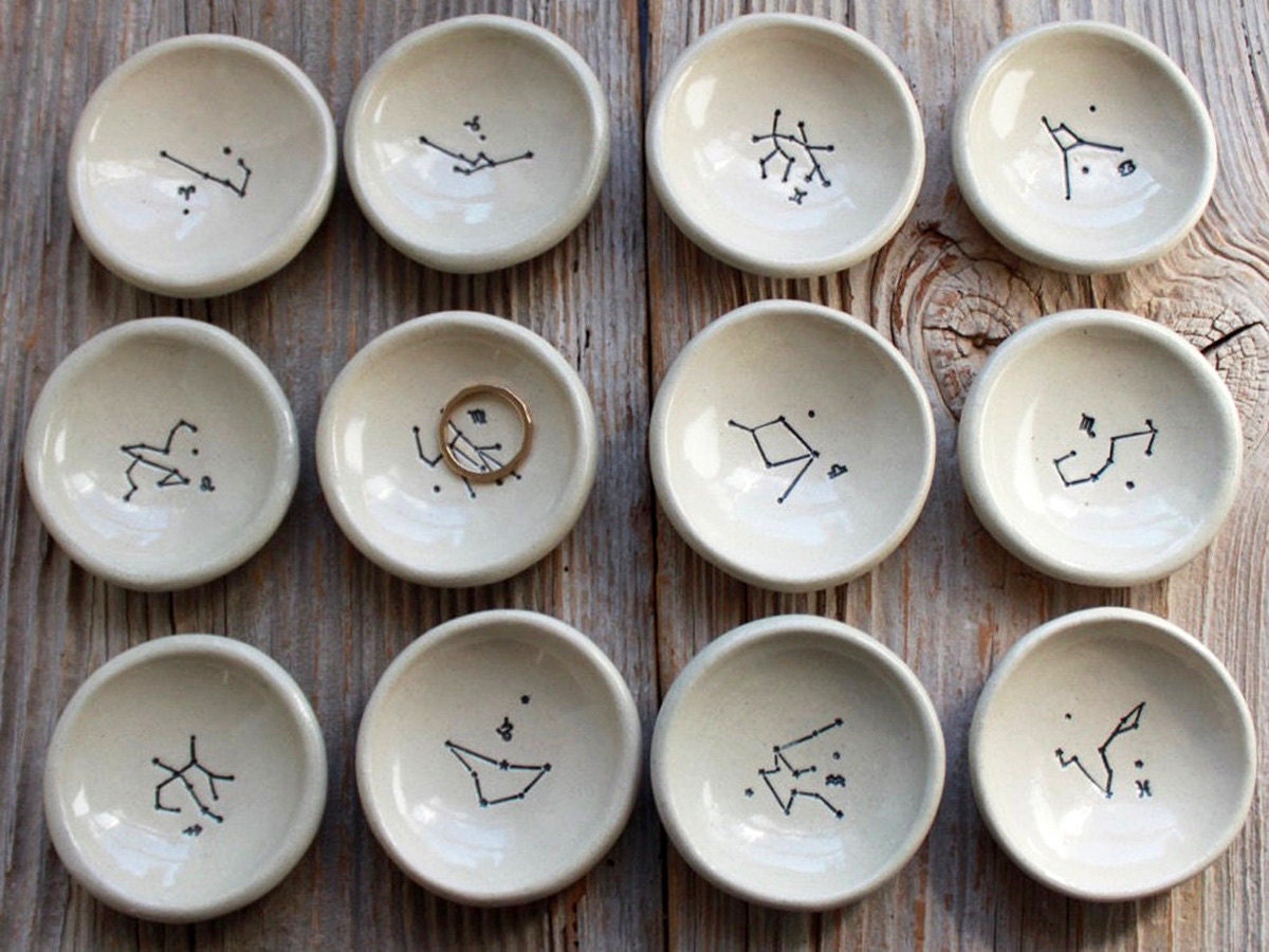 12 astrological ring dishes on a wooden background.