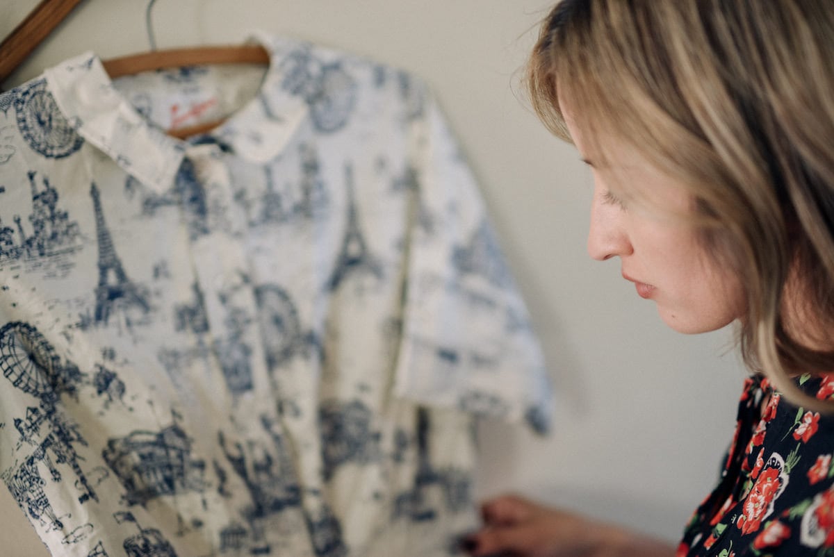 Yadira inspects a vintage dress hanging on the wall