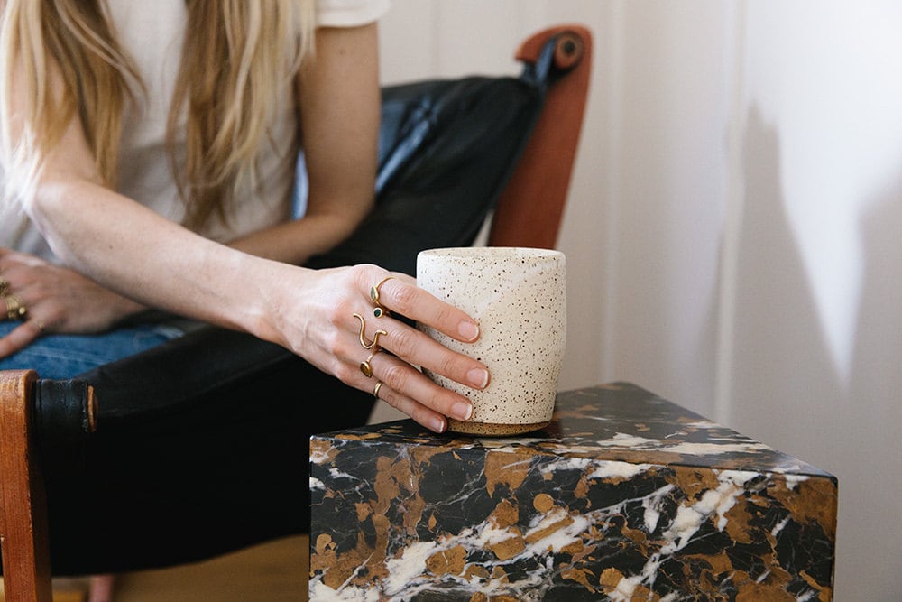 Sarah reaches for the speckled ceramic cup.