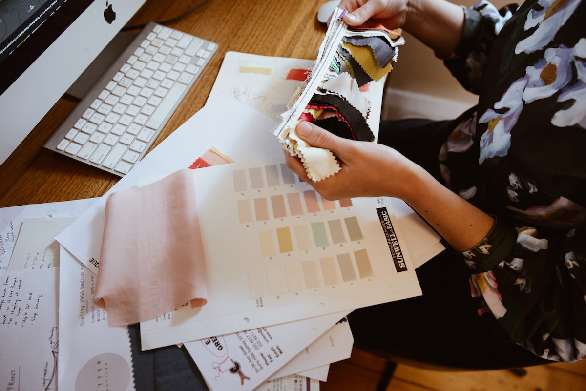 Rabia examining swatches of fabric in her office