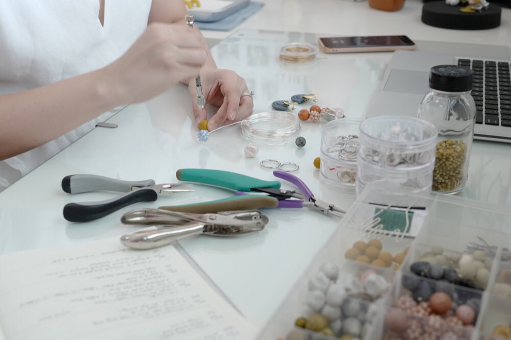 Jessica assembles an earring at her desk.
