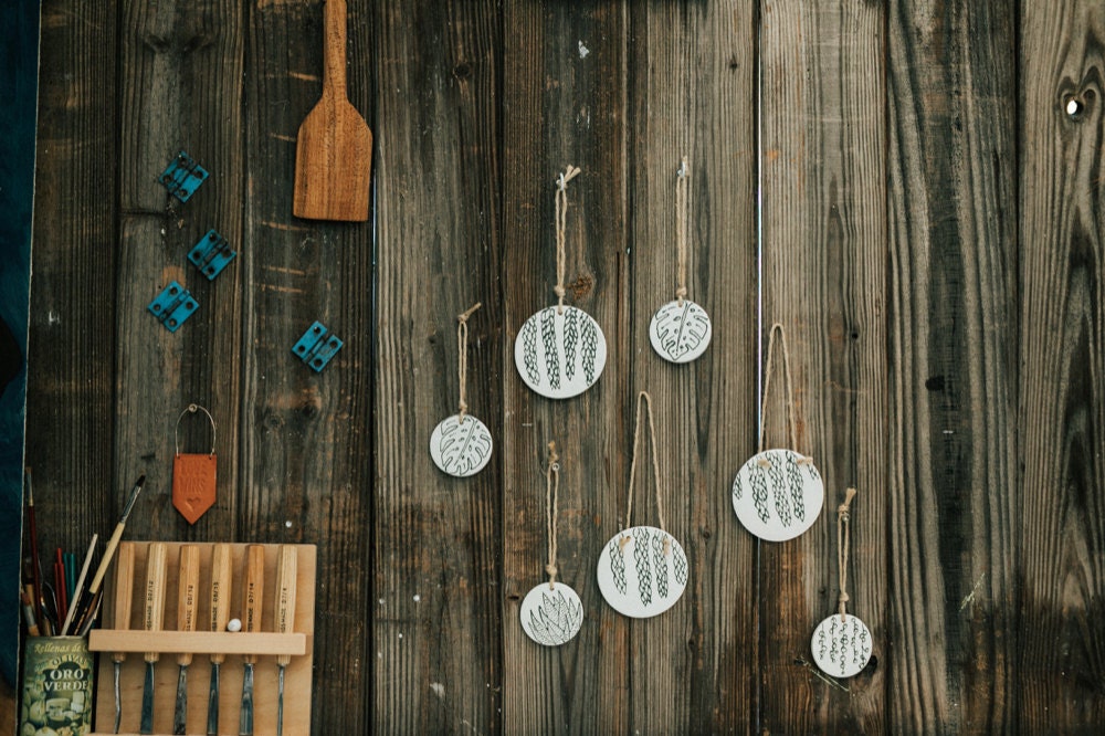 A set of Sally's ceramic, botanical-inspired ornaments hanging on a wall outdoors