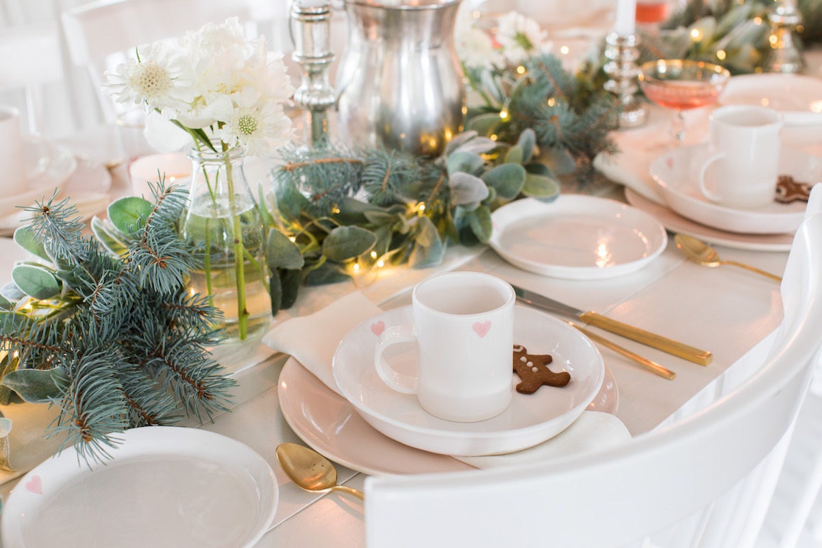 Holiday tabletop decorated with mixed greenery including eucalyptus and spruce