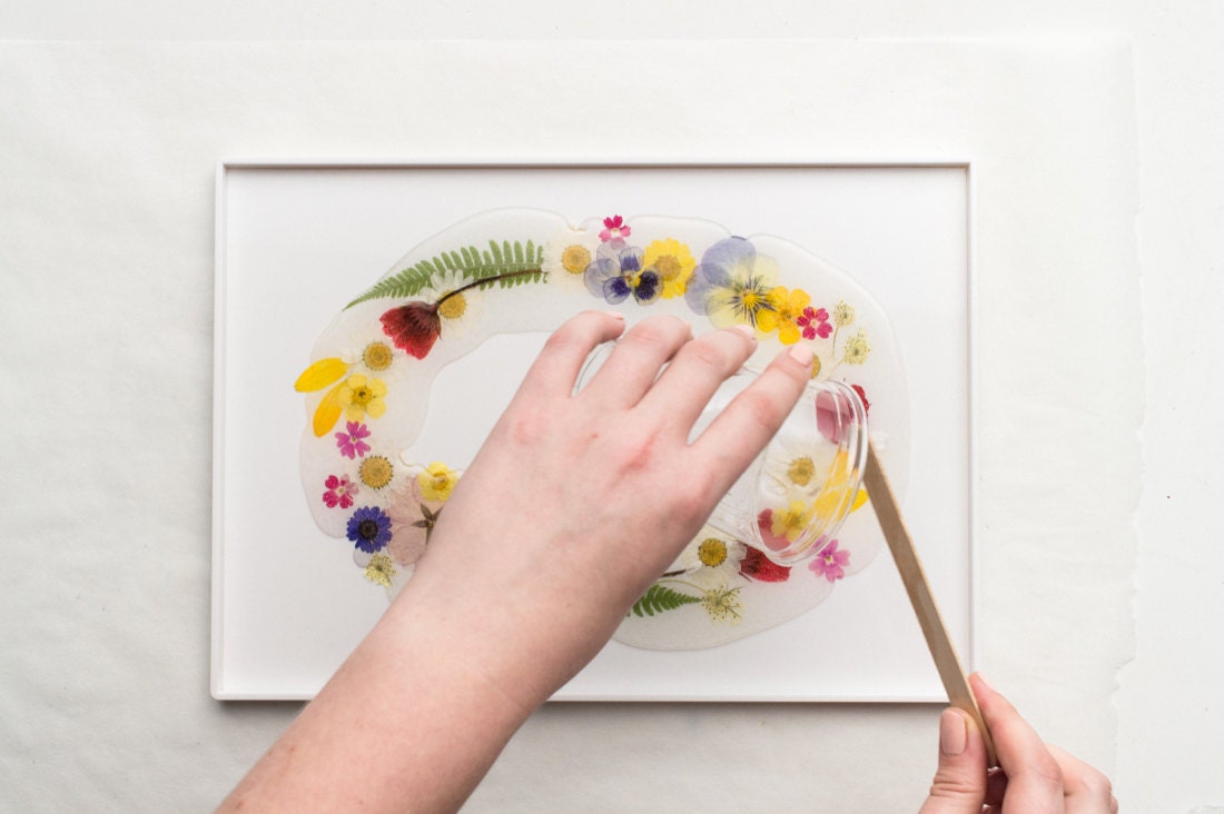 Pouring the resin over the floral arrangement on the tray