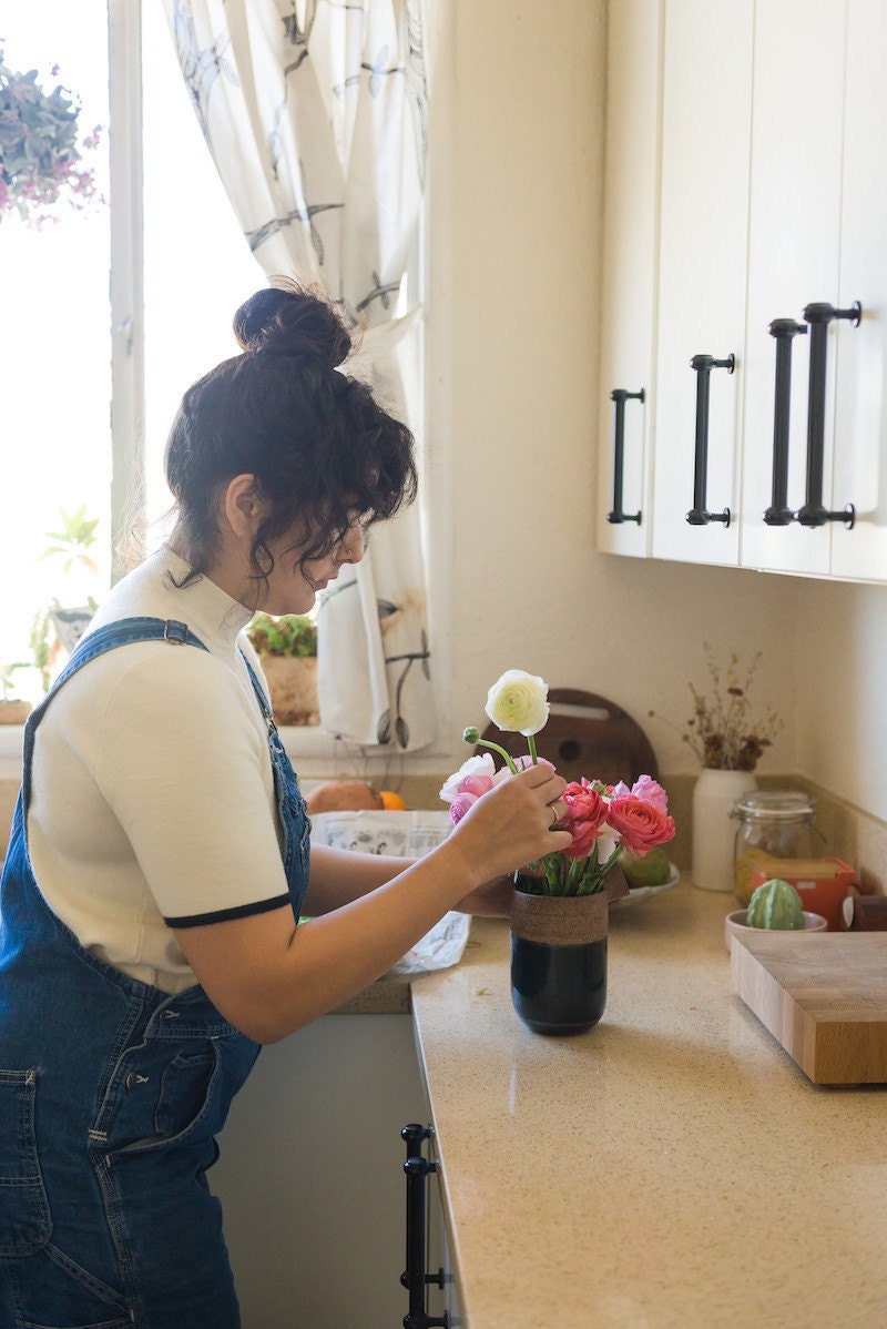 Melanie arranges flowers from the farmer's market in her kitchen