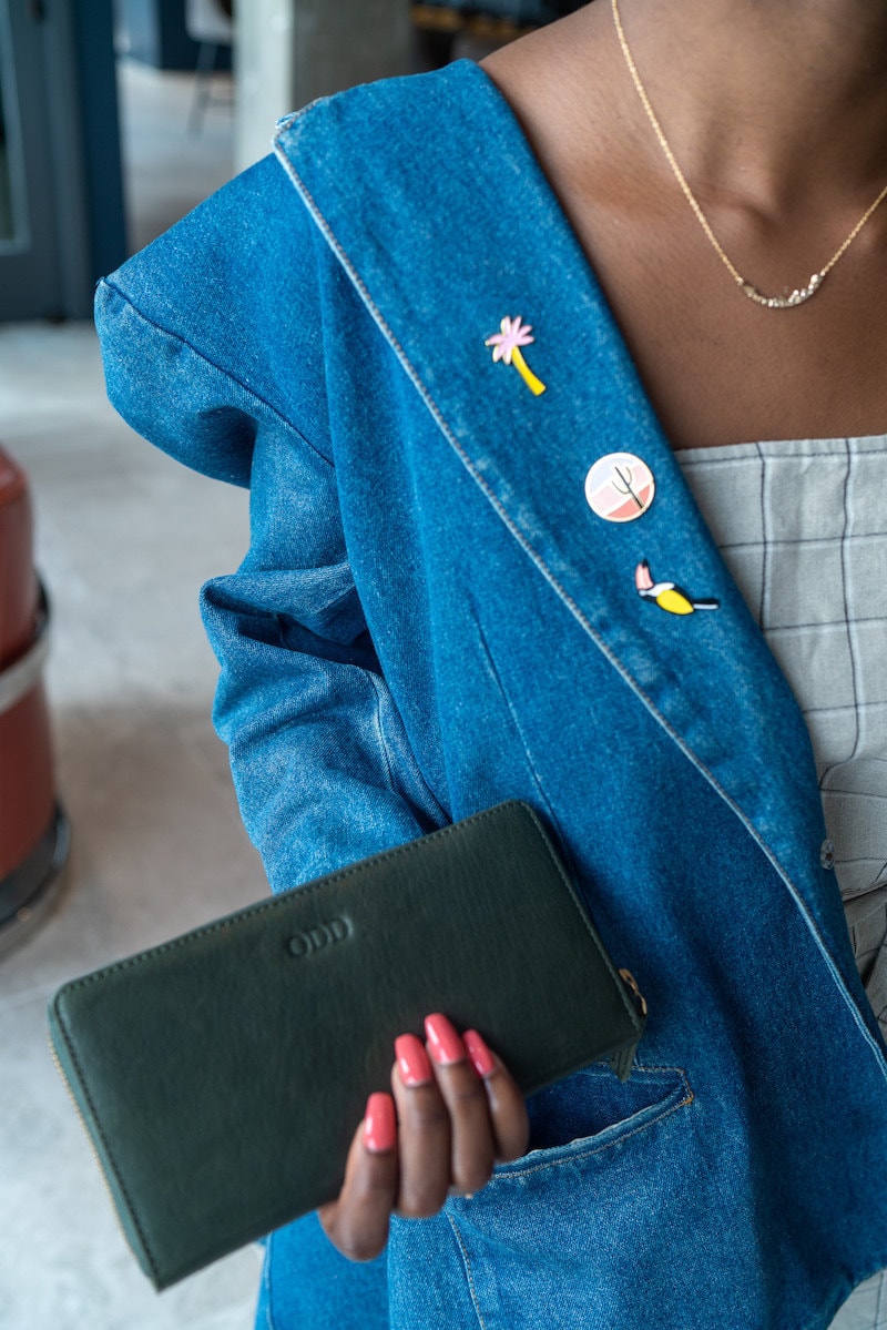 Sofi models a personalized leather wallet and colorful enamel pins from Etsy