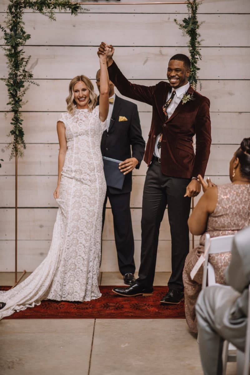 Emily and Terrell raise their hands in celebration of their I-dos