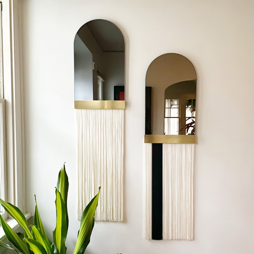 A "Svara" fringe arch mirror with brass accent bar from Candice Luter.