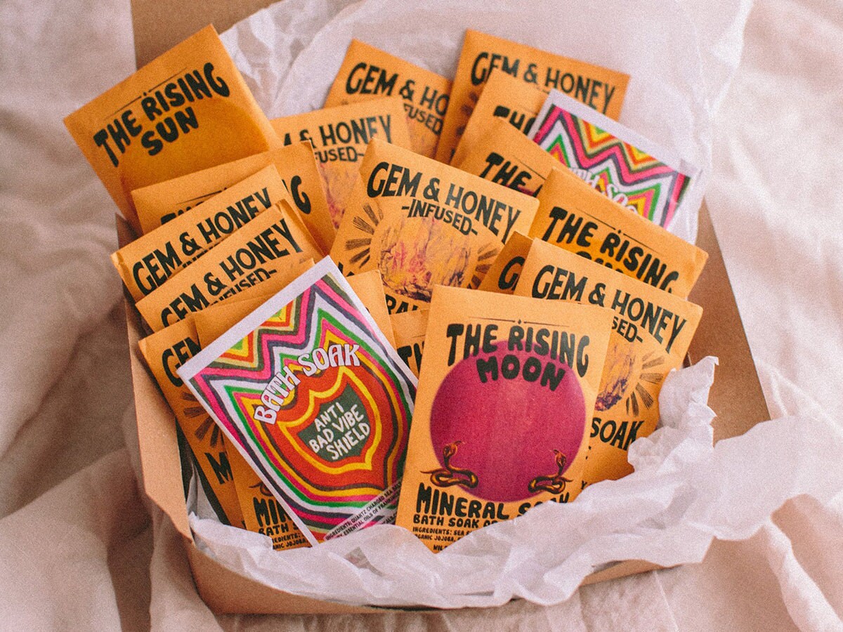 A set of bath salts, each packaged in yellow envelopes with bright illustrations and bold lettering.