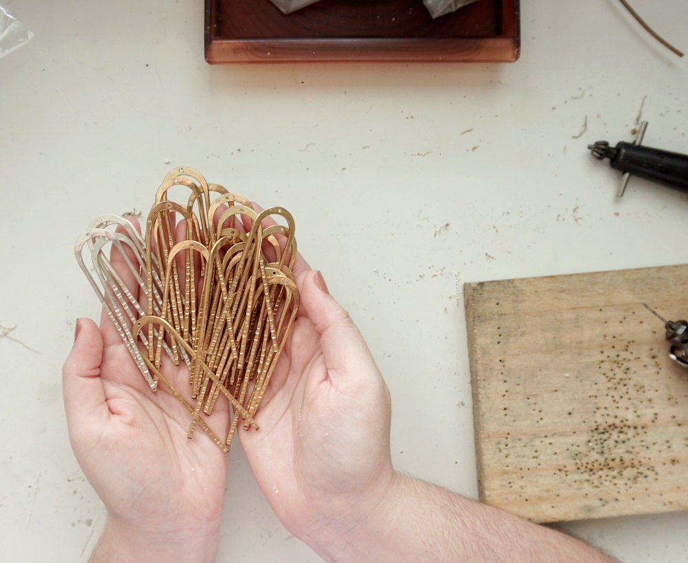 Aleishla holds an assortment of hammered silver and brass hairpins.