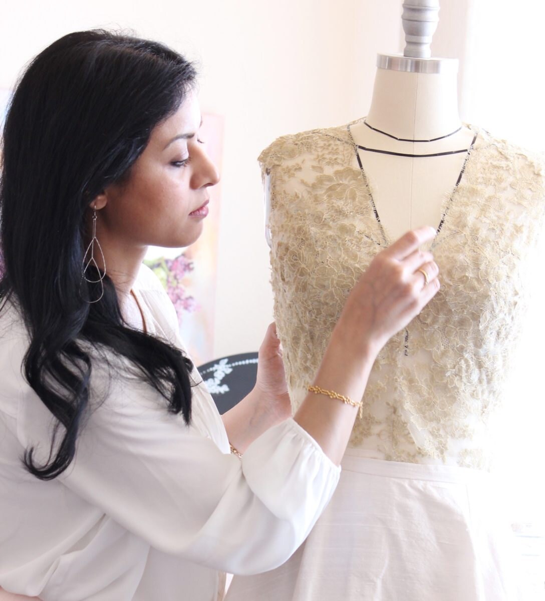 Smitha pins a gold lace bridal top on a form