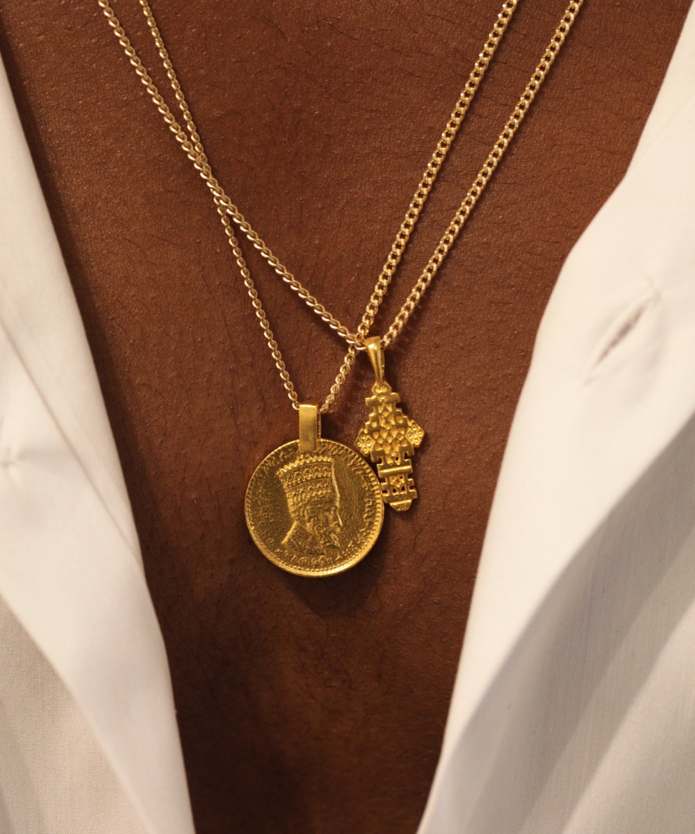 A man models an Ethiopian coptic cross and Rastafari coin necklace from Omi Woods