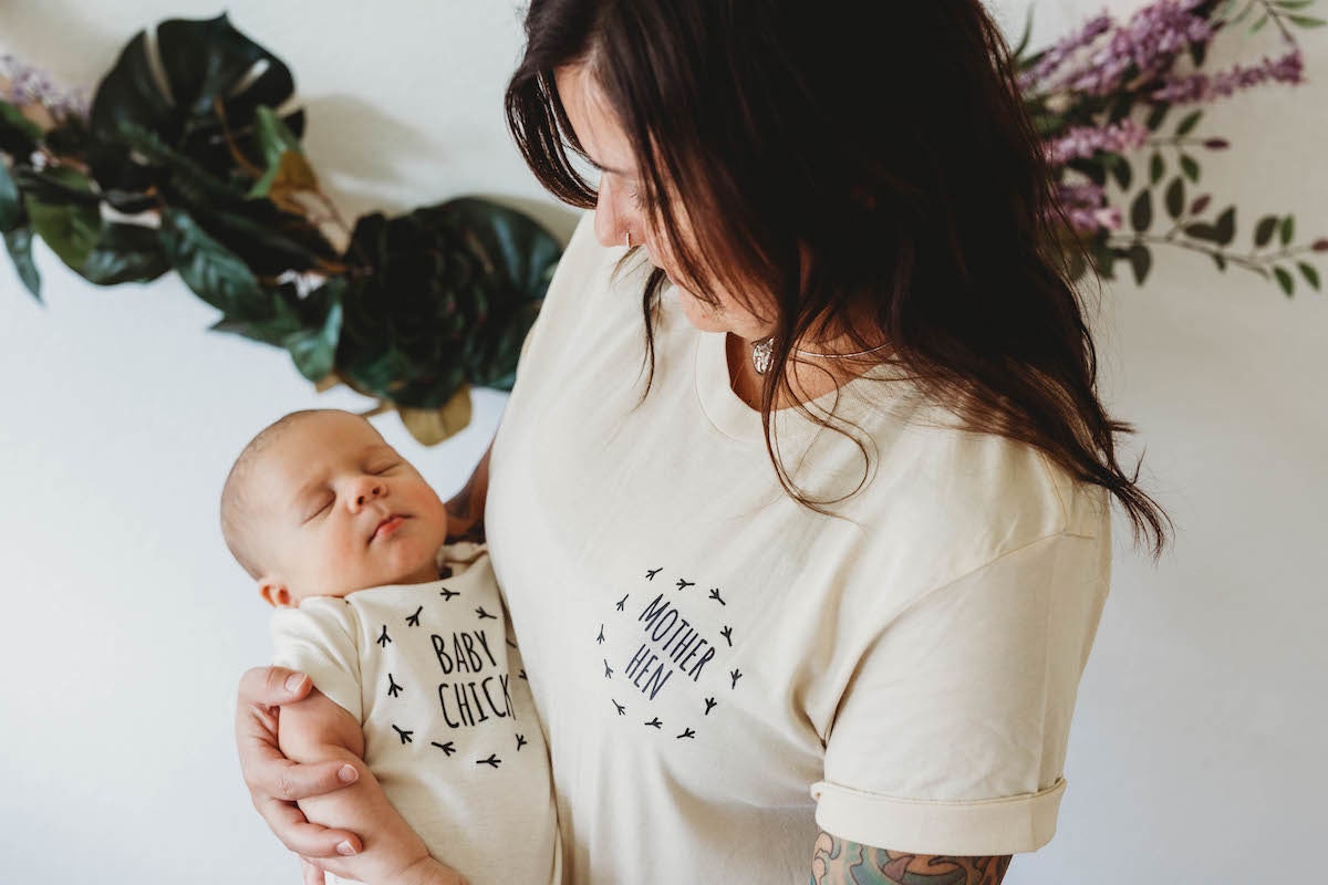 A mother wearing a "Mother Hen" T-shirt holds a baby wearing a "Baby Chick" T-Shirt