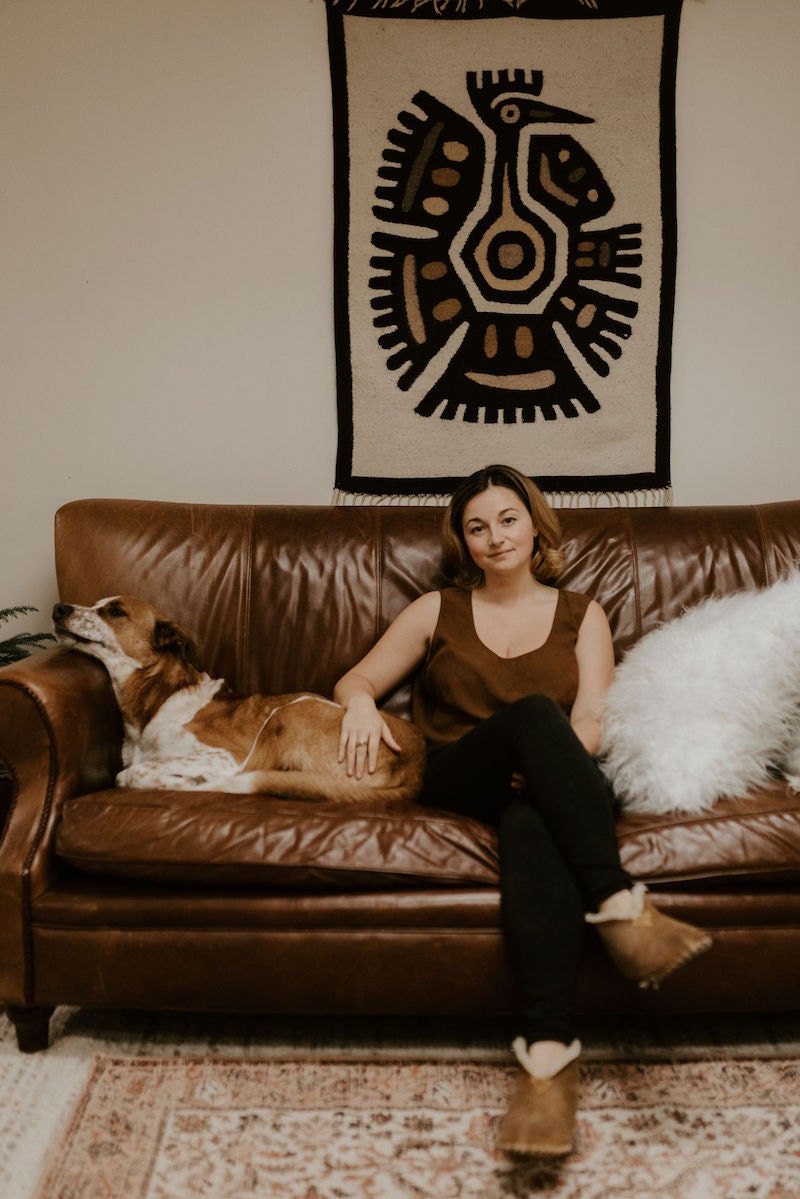 Alicia sitting on her couch with her dog