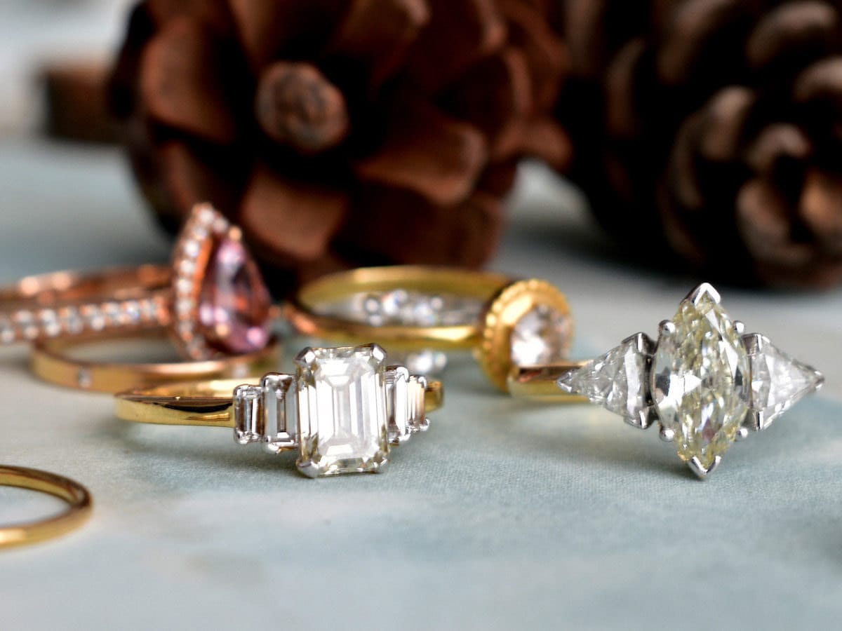 Four sparkling engagement rings displayed on a gray surface