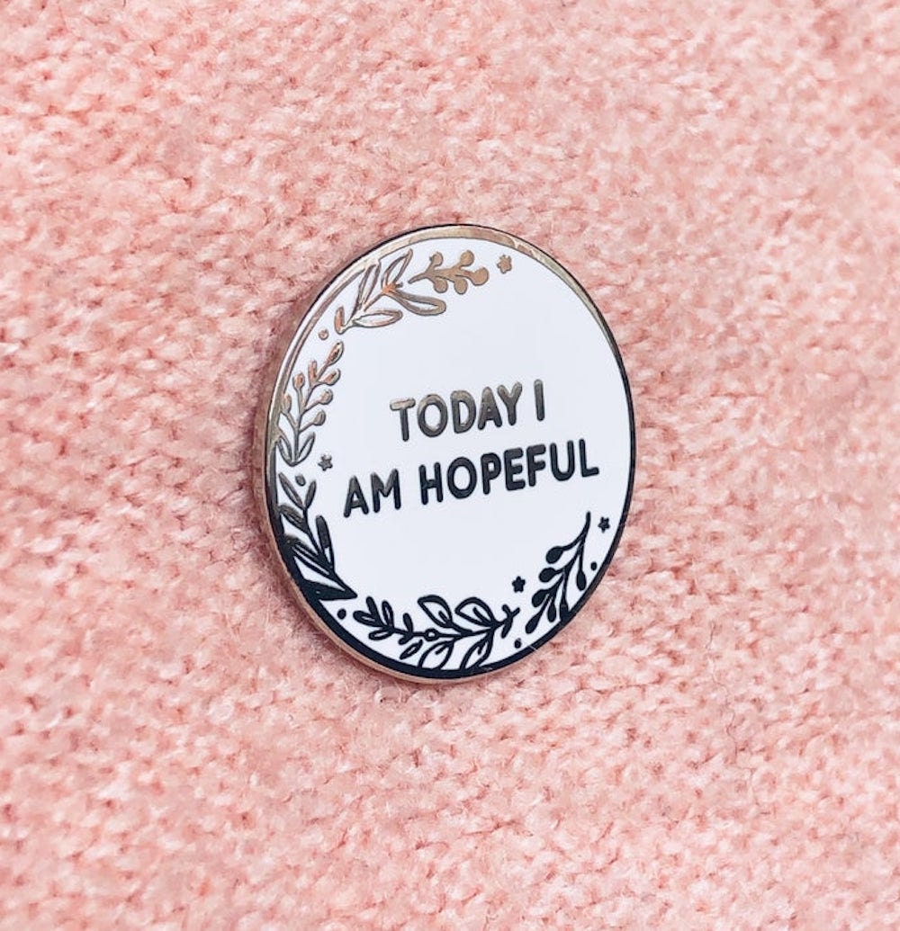An enamel pin from Clara and Macy that reads "Today I Am Hopeful."