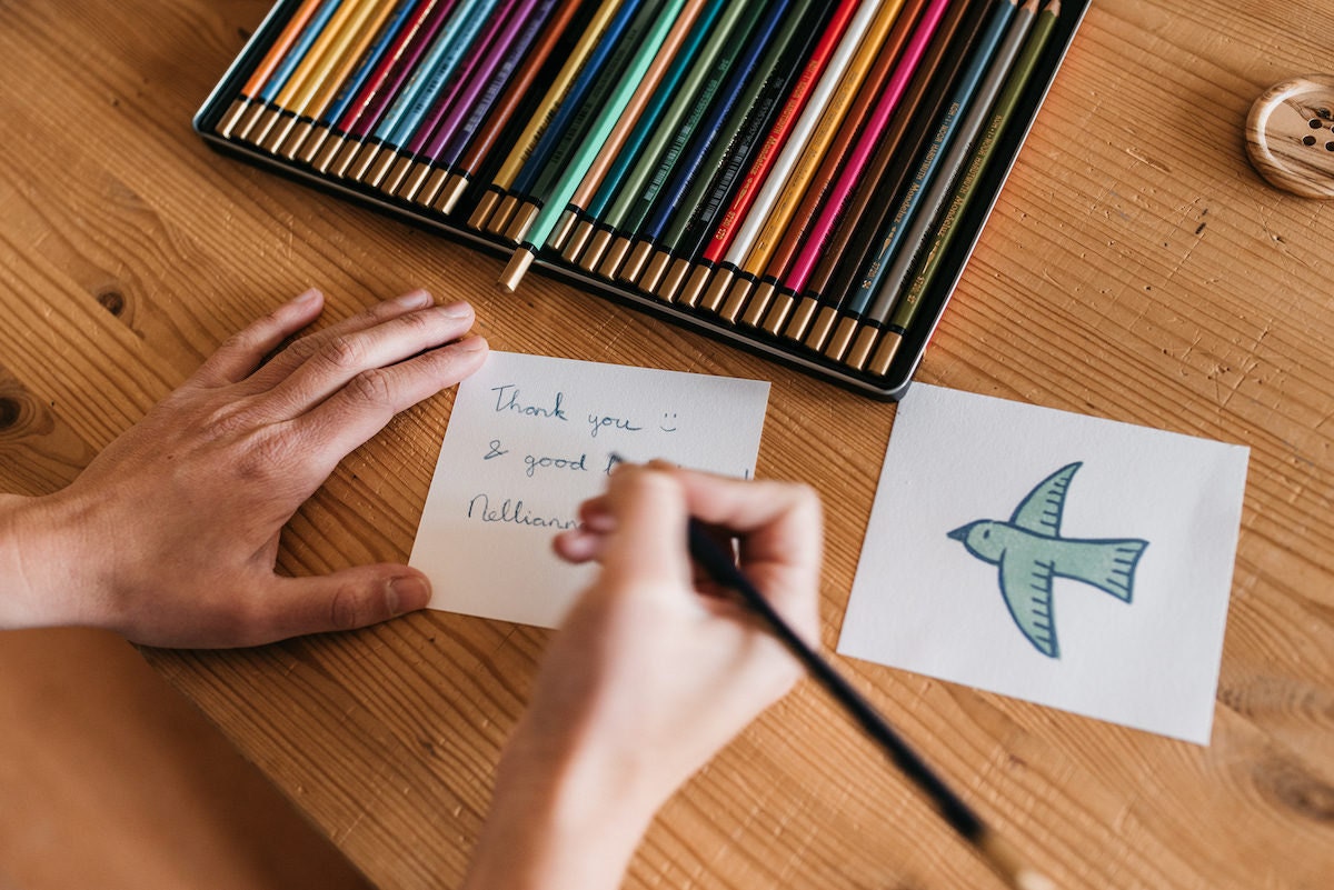 Nellianna writes a thank you card for a customer in colored pencil