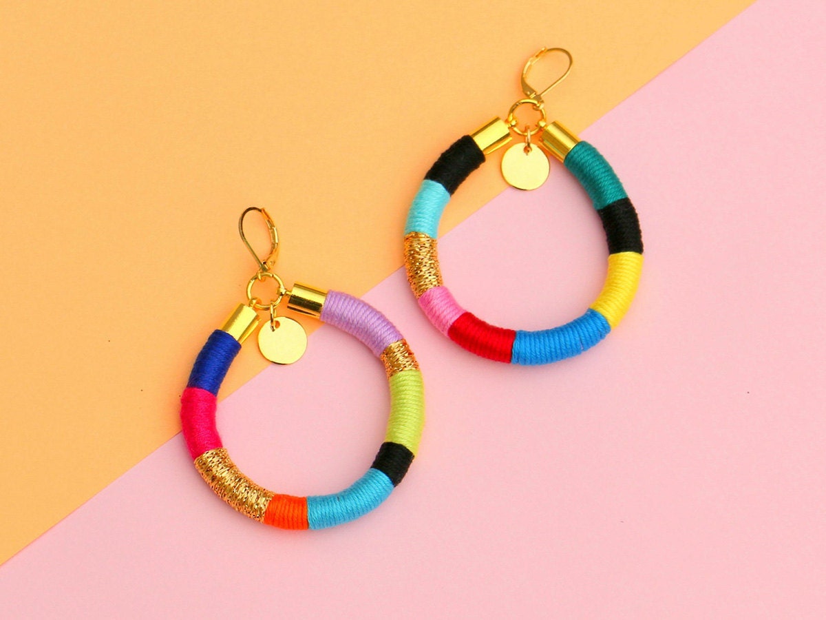 Colorful hoop earrings against a pink and orange background.