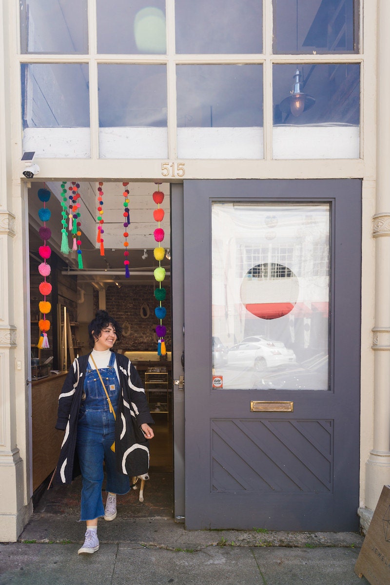 Melanie and Rover walk out the colorful front door of Oakland's Crown Nine boutique