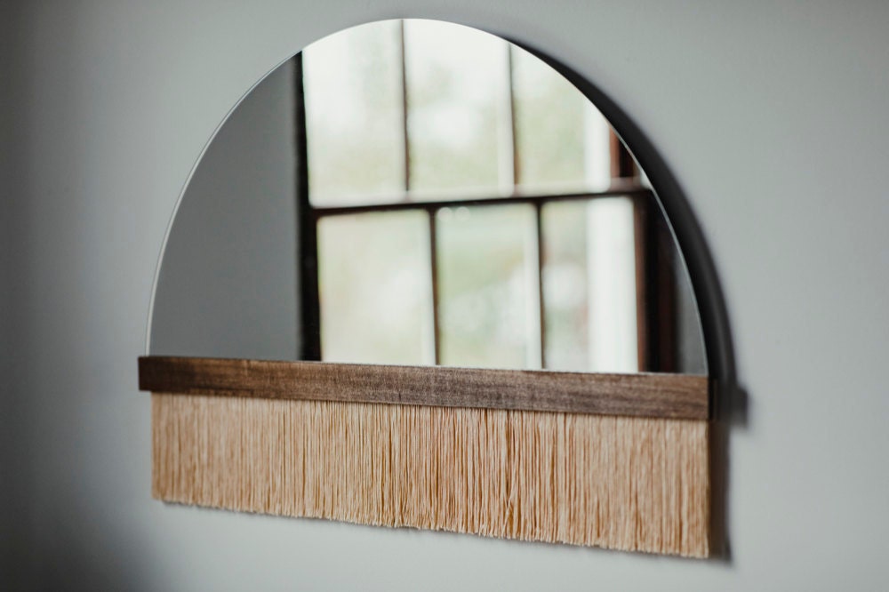 A large "Aria solo" fringe mirror with wood bar and peach dip-dyed fringe from Candice Luter.