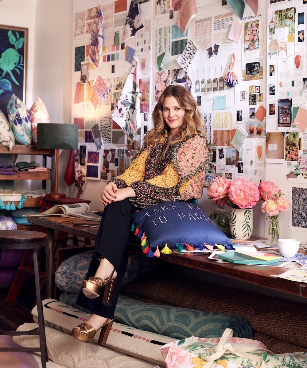 Portrait of Drew Barrymore in front of a fabric mood board.