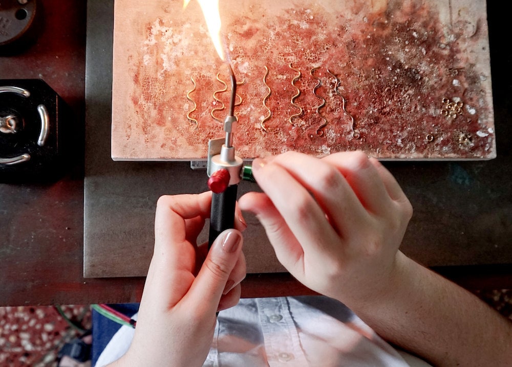 Aleishla uses a blow torch to solder her pieces together.