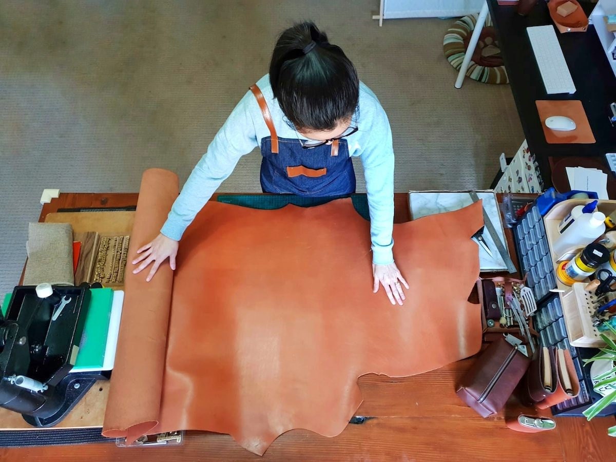 Pauline unfurls a scroll of leather in her home studio