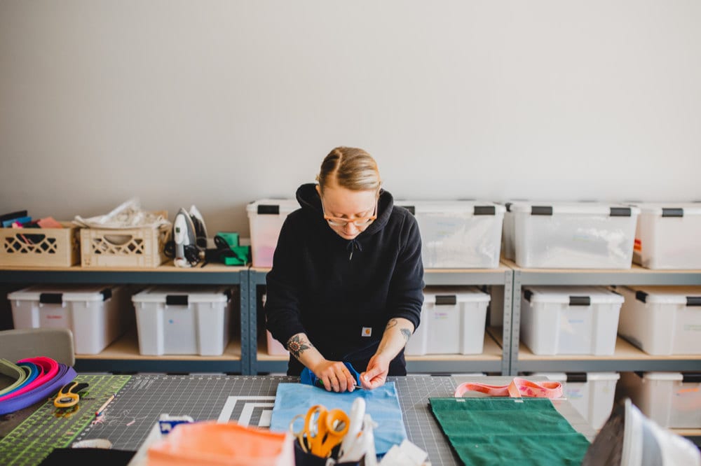 Hanna sews a strap onto a market bag in her sewing studio.